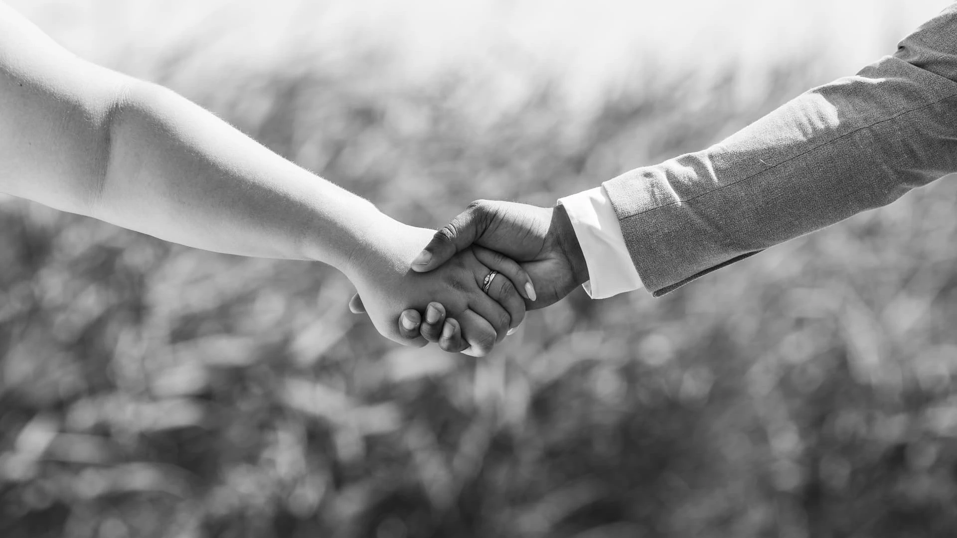 Zwart-witfoto van een bruidspaar dat elkaars hand vasthoudt op hun trouwdag